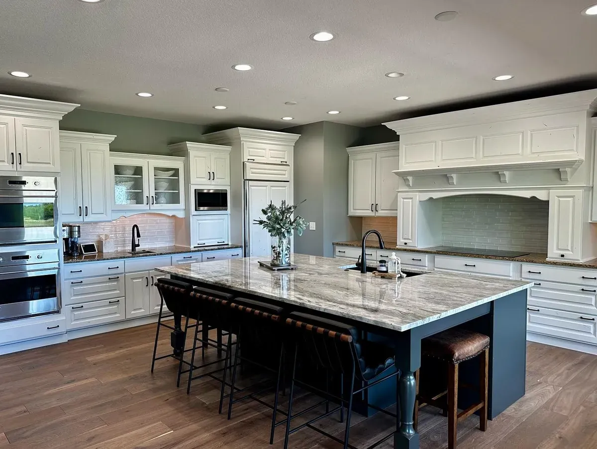 Large kitchen with white cabinets, a granite island and plank flooring